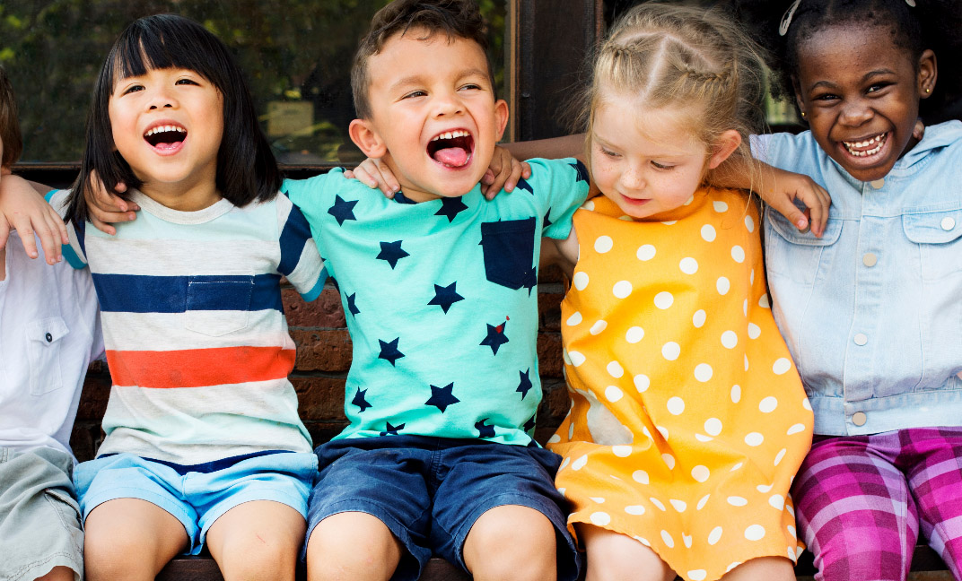 Toddlers sitting on bench making funny faces