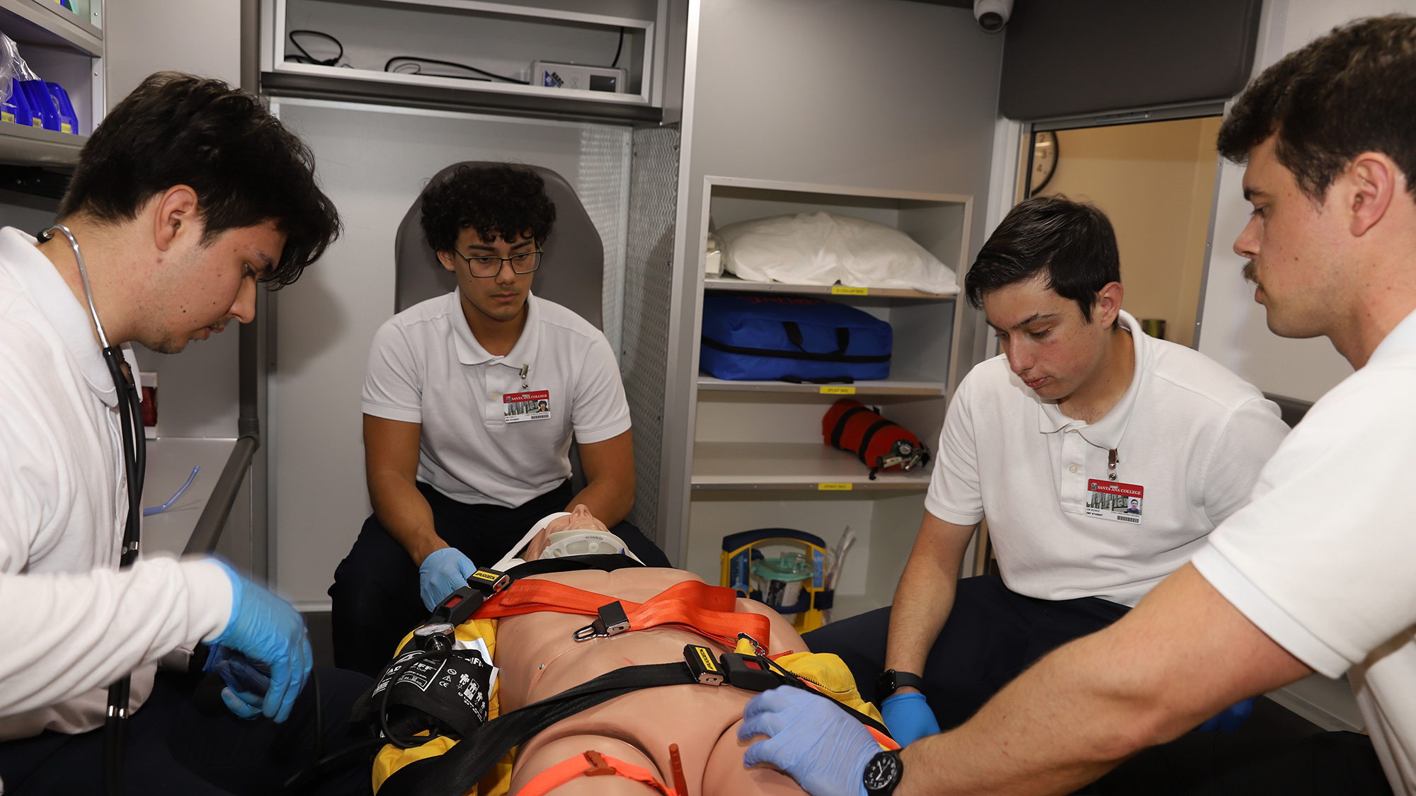 Four EMT students practicing on a model