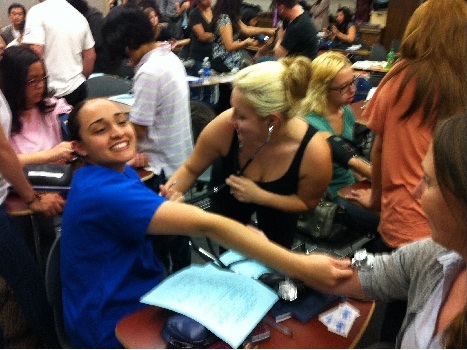 student enthusiastically offering arm to have blood pressure taken by other students