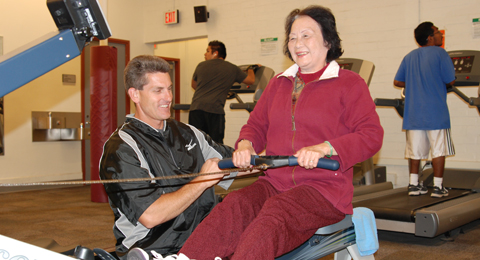 Doctor Sos helping an attendee with the rowing machine. 