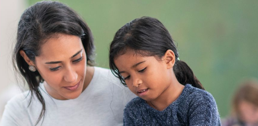 Female teacher assisting young hispanic girl