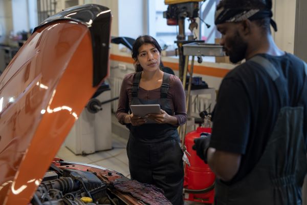 female hispanic student and male black student both working on a car
