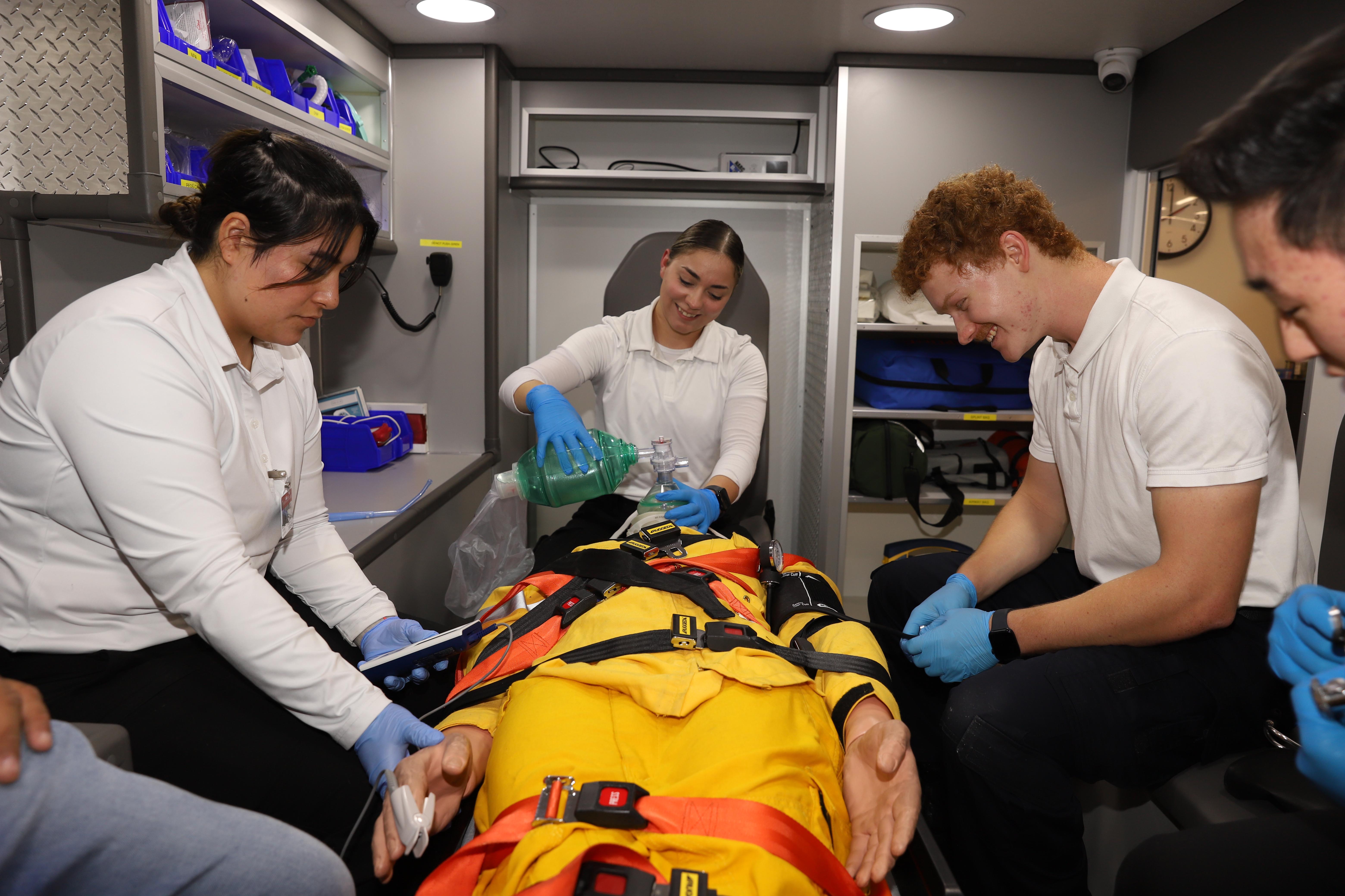 two female and one male emt students practicing Resuscitation on a dummy in a simulated ambulance