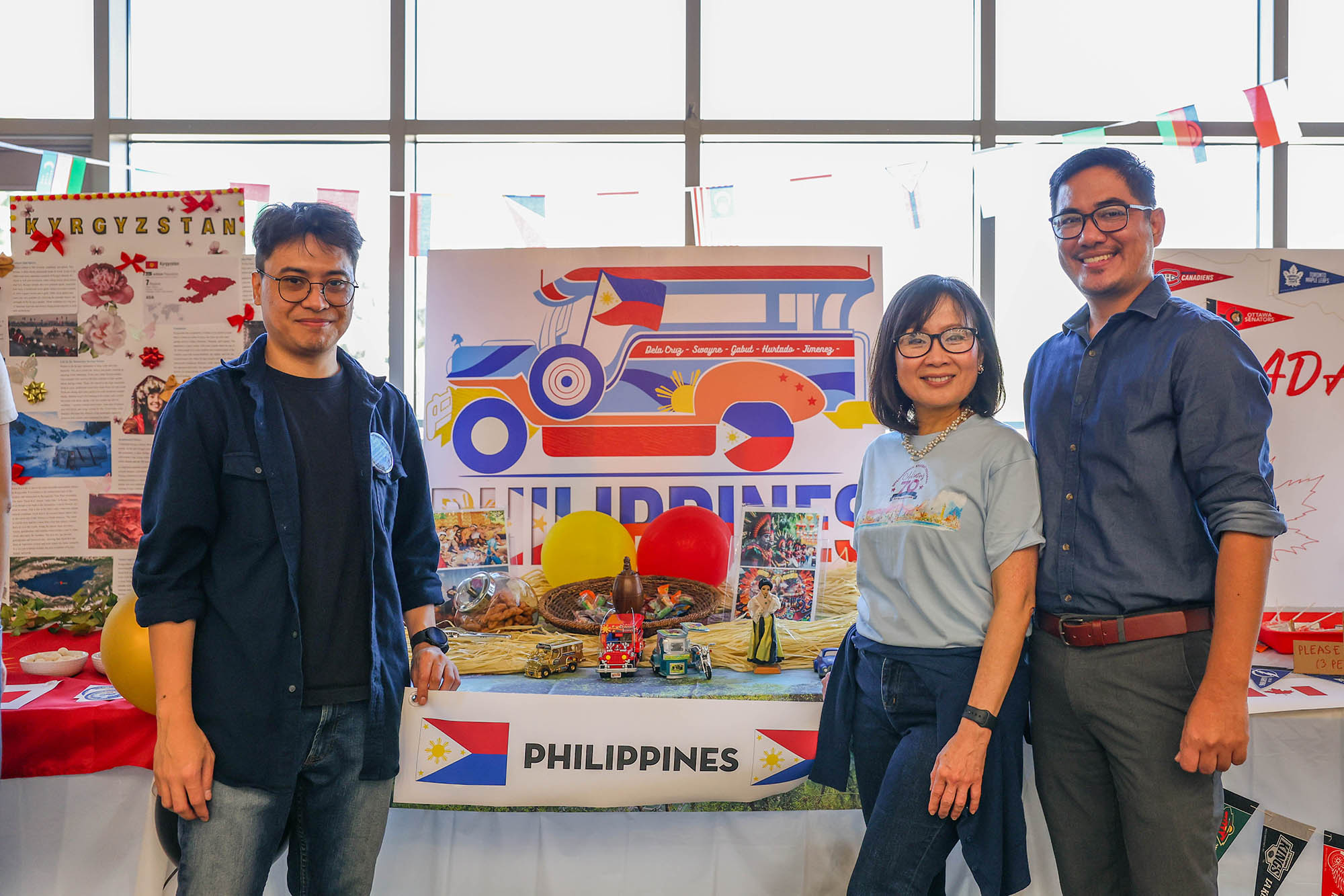 Filipino student in front of his cultural booth alongside two staff members