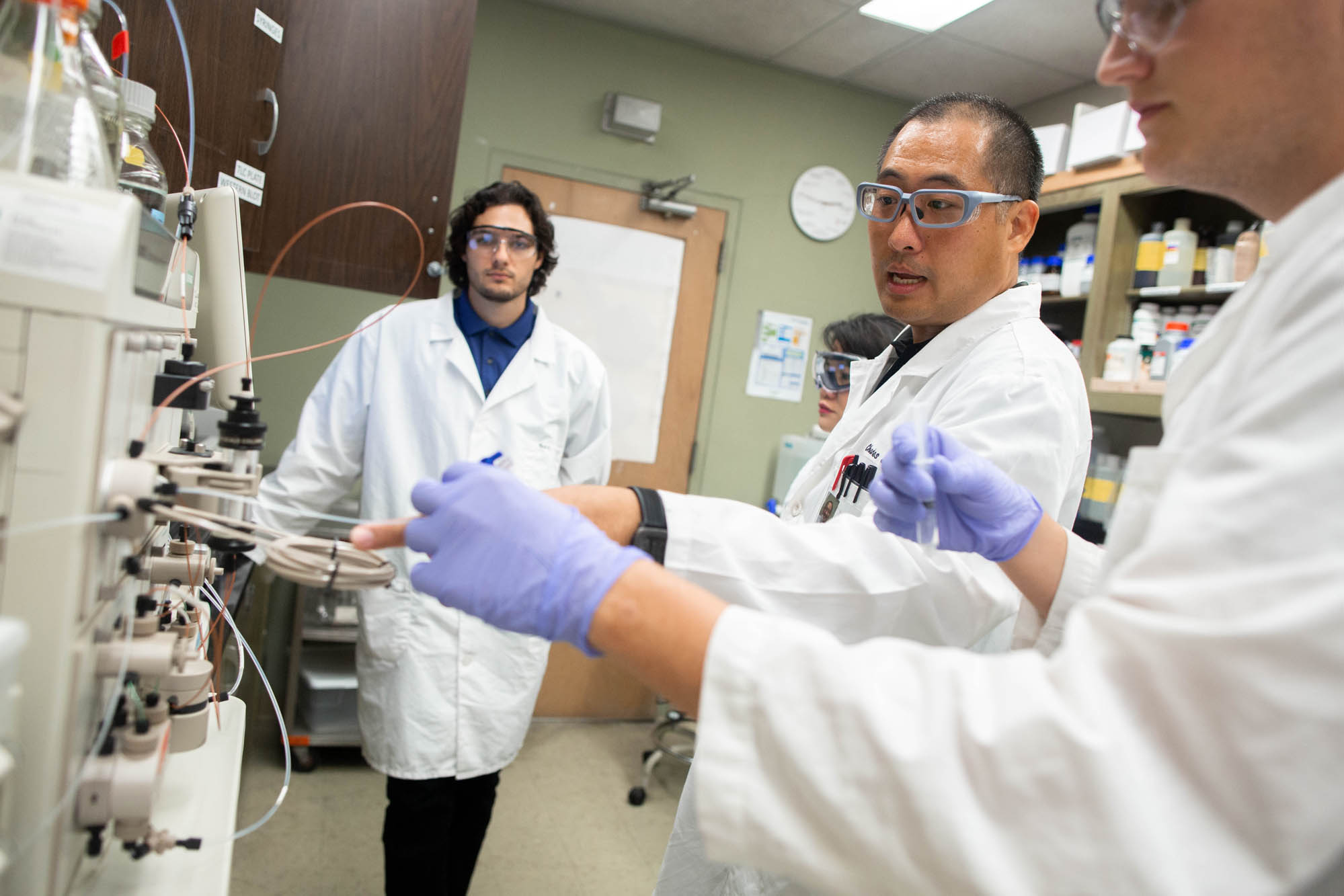 Asian instructor supervising two students in a lab