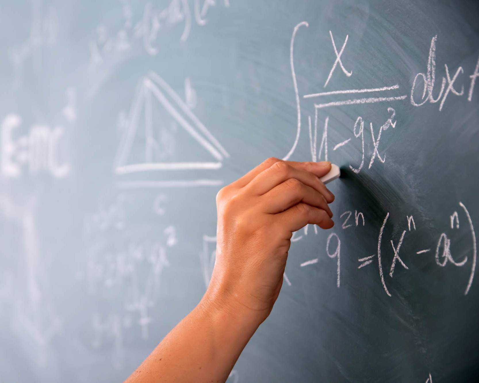 someone solving math equation on chalkboard
