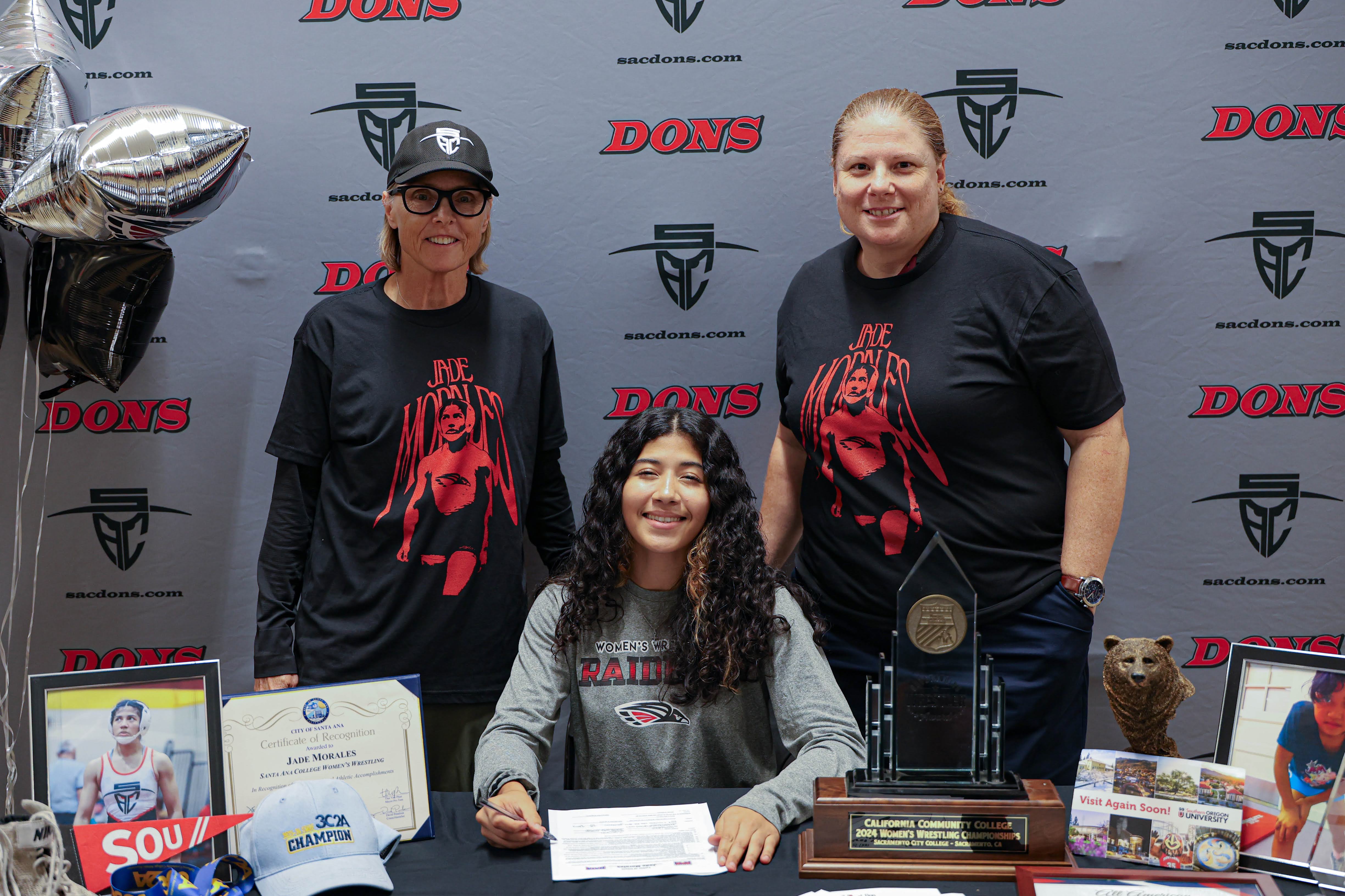 Jade Morales signing her letter of intent with Athletic Director Mary Hegarty and Dean of Kinesiology Andrea Picchi behind her. 