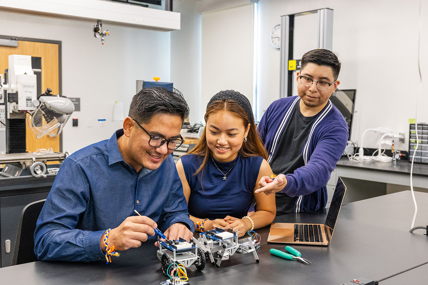 Tony (left), My Le (center), and Arthur (right) work together on a robot at the school's lab.