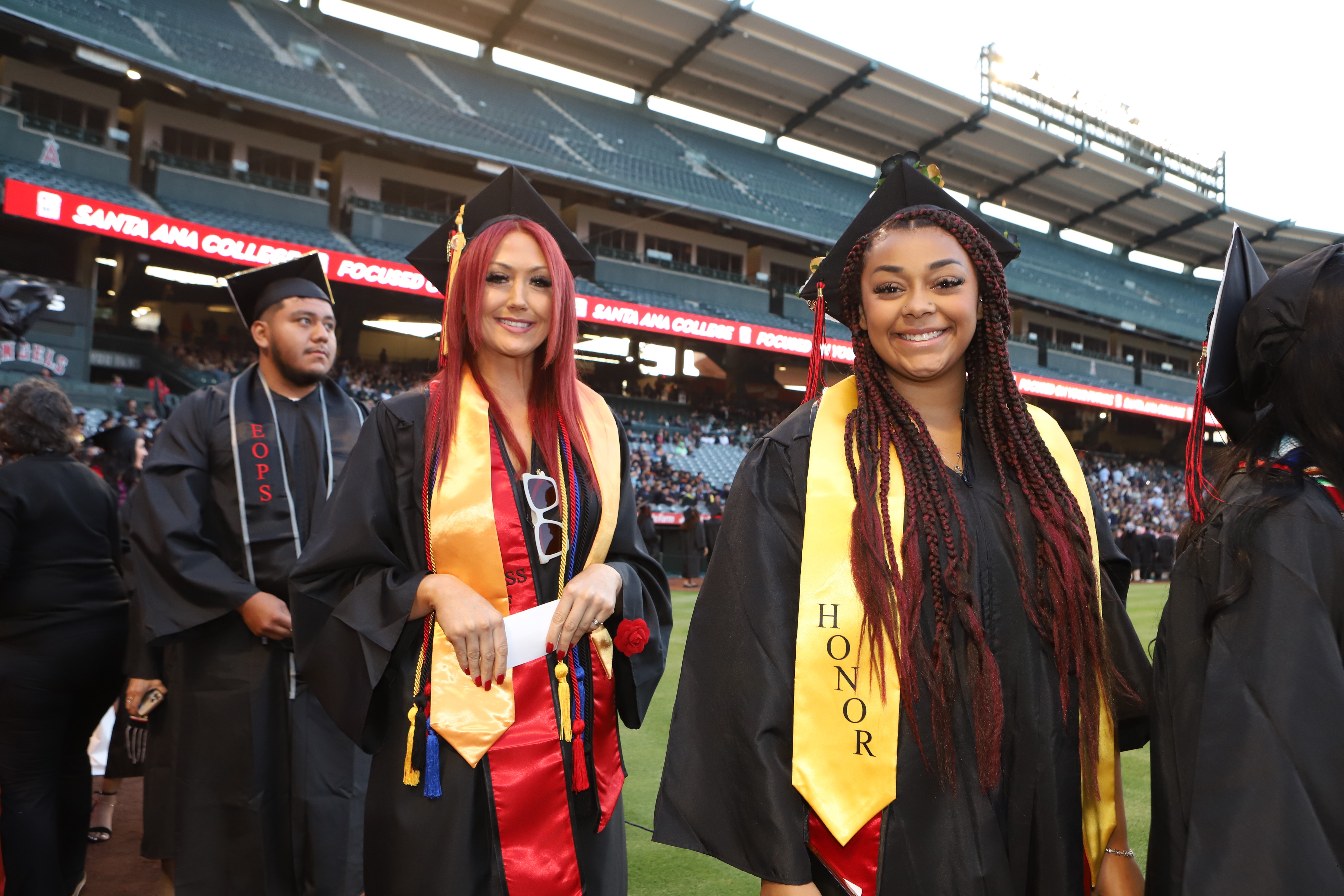 three students line up to receive diploma at commencement