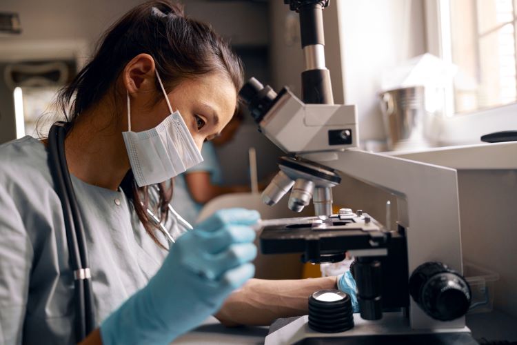 Asian woman working with medical lab equipment after finishing biotechnology program at Santa Ana College