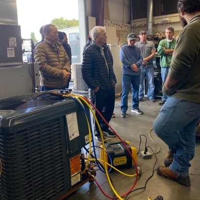 Man in green hat performing HVAC maintenance after getting certification from continuing education
