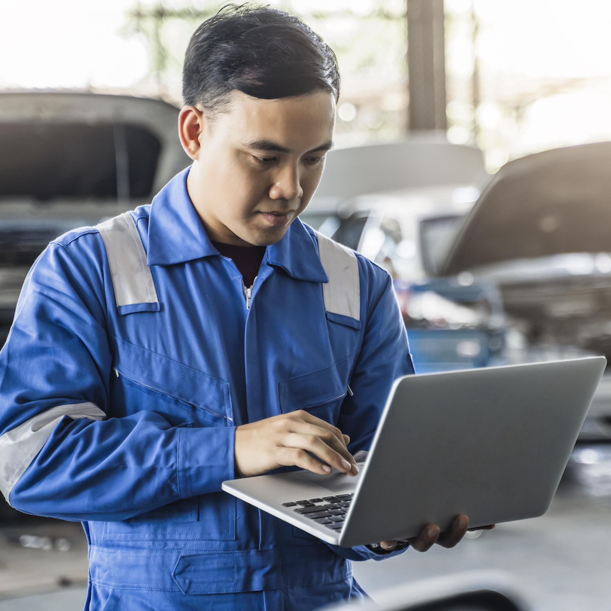 Asian automechanic working on a car in a autoshop