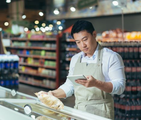 Asian grocery store employee reading work information with skills from English class with Continuing Education