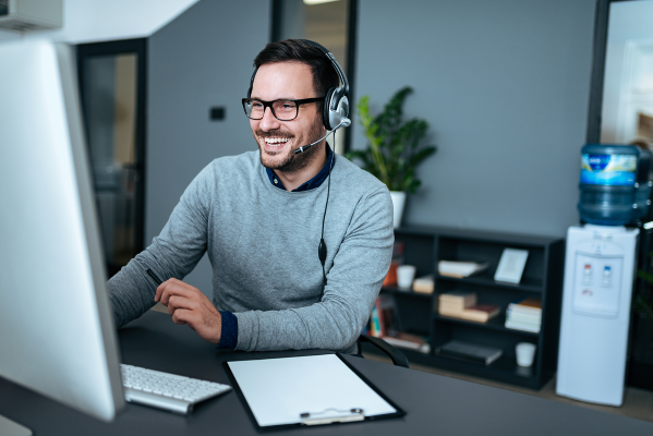 Smiling caucasian man taking phonecalls as customer service representative, using the skills learned with continuing education