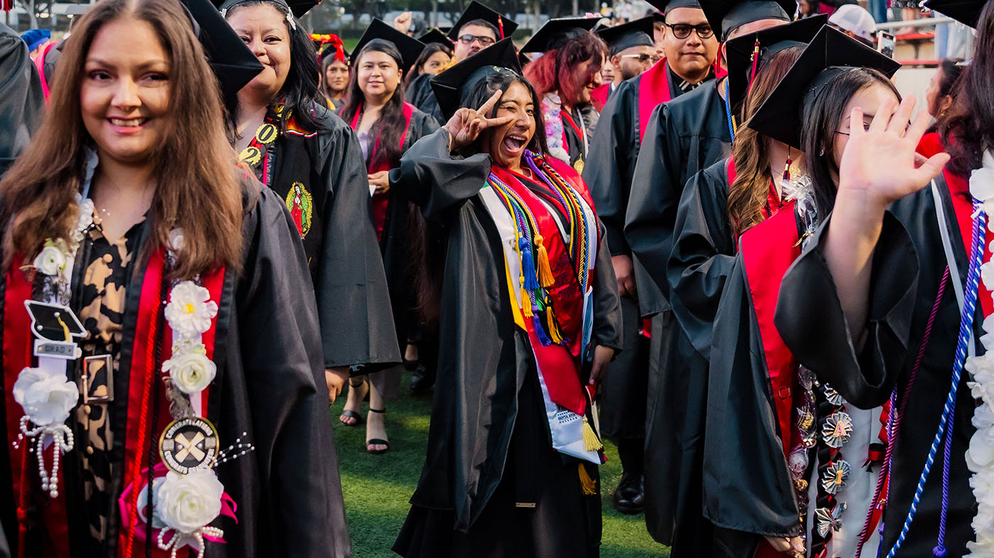 female student in cap and gown posing with peace sign